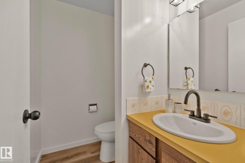 White vanity with an oval sink, dark bronze faucet, and bright yellow countertop - 14411 23 Street Nw, Edmonton, AB 