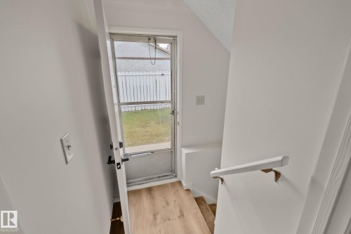 Light wood-finish flooring with a white handrail and white painted walls - 14411 23 Street Nw, Edmonton, AB 
