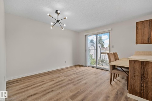 Wood-finish flooring, contemporary ceiling light fixture, sliding glass door, and wood-finish cabinetry - 14411 23 Street Nw, Edmonton, AB 