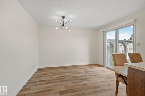 Wood-finish flooring, sliding glass door, contemporary ceiling fixture, textured ceiling, and neutral wall finishes - 14411 23 Street Nw, Edmonton, AB 