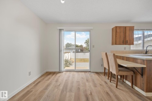 Wood-finish flooring, white walls, sliding glass door, wood-finish cabinetry, and built-in breakfast bar - 14411 23 Street Nw, Edmonton, AB 