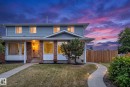 Blue siding exterior with brick accents, bay window, front entry with covered porch, and a wood privacy fence - 14411 23 Street Nw, Edmonton, AB 