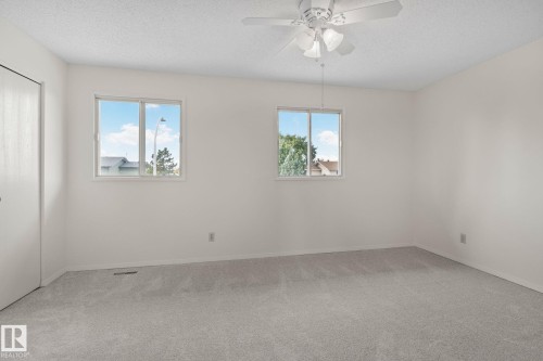 Neutral wall finishes, textured ceiling, carpet flooring, dual windows, and a ceiling fan with integrated lighting - 14411 23 Street Nw, Edmonton, AB 