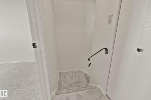 Carpeted staircase with a matte black wall-mounted handrail - 14411 23 Street Nw, Edmonton, AB 