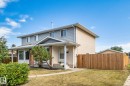 Two-story residence featuring siding and stucco exterior, a covered entryway, mature landscaping, and a privacy fence - 14411 23 Street Nw, Edmonton, AB 