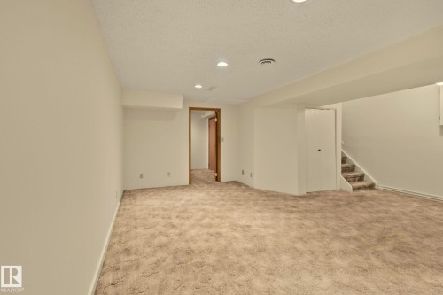 Expansive open room featuring plush carpet flooring, recessed lighting, and a neutral wall palette - 14411 23 Street Nw, Edmonton, AB 