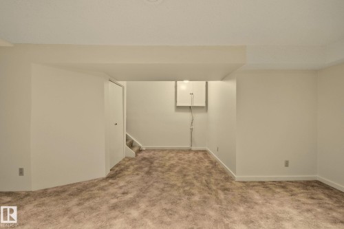 Neutral-toned wall paint, textured carpeting, white trim, and a built-in wall cabinet - 14411 23 Street Nw, Edmonton, AB 