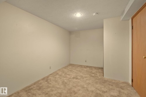 Recessed ceiling lighting, textured ceiling finish, neutral wall tones, light brown carpet, and a wood-finish door - 14411 23 Street Nw, Edmonton, AB 