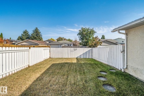 Private backyard with white picket fencing, stone stepping path, and mature landscaping - 14411 23 Street Nw, Edmonton, AB 