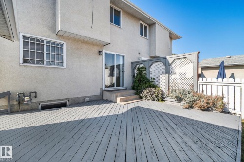 Exterior deck area featuring a stucco facade, sliding glass door, and lattice privacy screening - 14411 23 Street Nw, Edmonton, AB 
