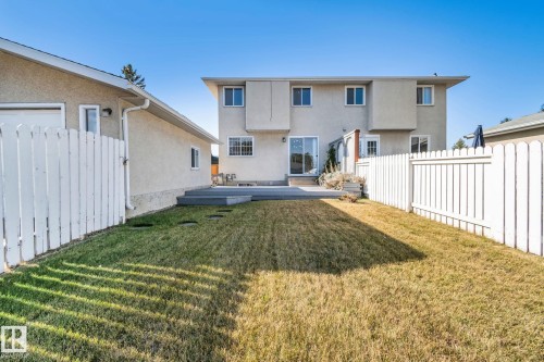 Expansive fenced backyard with a patio deck, mature trees, and a detached garage - 14411 23 Street Nw, Edmonton, AB 