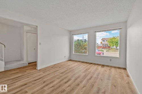 Wood-finish flooring throughout, bright white walls, and dual windows allowing natural illumination - 14411 23 Street Nw, Edmonton, AB 