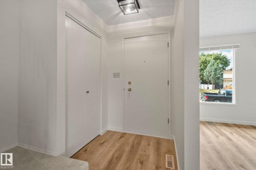 Entryway featuring wood-finish flooring, white walls, and a contemporary flush-mount ceiling light - 14411 23 Street Nw, Edmonton, AB 