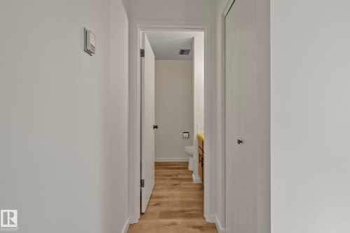 Hallway with light wood-finish flooring and white walls - 14411 23 Street Nw, Edmonton, AB 