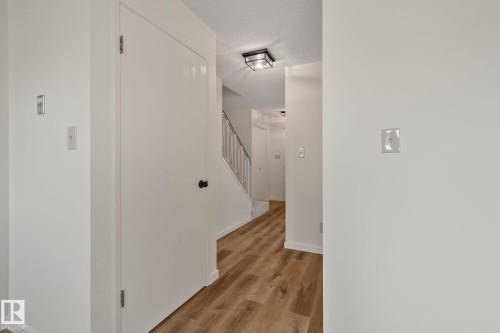 Wood-finish flooring, staircase with metal railing, and a modern ceiling fixture - 14411 23 Street Nw, Edmonton, AB 