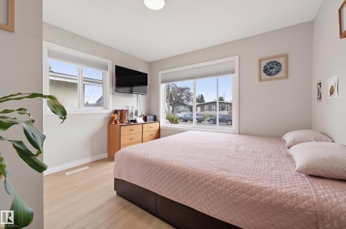 Light-toned wood-finish flooring with white baseboards, bright windows, and neutral wall paint - 9020 152 Street Nw, Edmonton, AB 