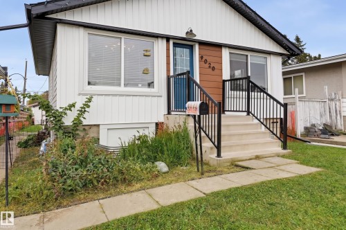 Entry steps with black metal railings, a blue front door, and a wall-mounted outdoor light fixture - 9020 152 Street Nw, Edmonton, AB 