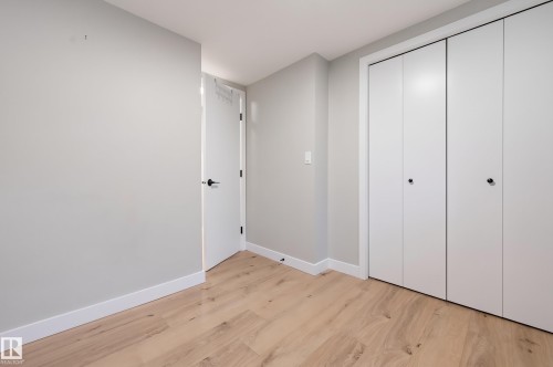 Wood-finish flooring, white walls, and a white door with matte black hardware - 9020 152 Street Nw, Edmonton, AB 