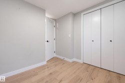 Wood-finish flooring, white walls, and a white door with matte black hardware - 
