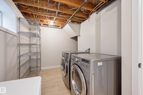 Laundry area featuring light wood-finish flooring, white walls, and a window - 9020 152 Street Nw, Edmonton, AB 
