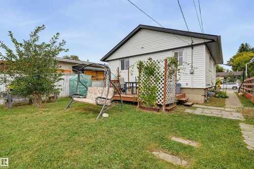Rear exterior featuring white horizontal siding, a wood-finish deck, and a grass lawn - 9020 152 Street Nw, Edmonton, AB 
