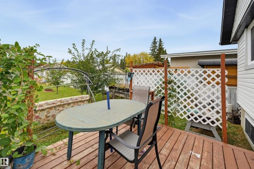 Wood-finish deck with white lattice privacy screen and stone retaining wall - 9020 152 Street Nw, Edmonton, AB 