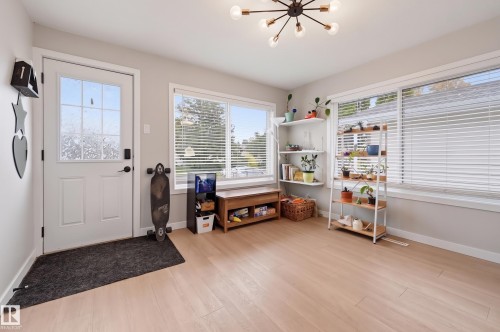 Entryway featuring wood-finish flooring, multiple windows, a transom door, and a sputnik-style ceiling fixture - 9020 152 Street Nw, Edmonton, AB 