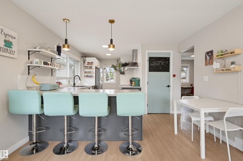 Kitchen with wood-finish flooring, an island with countertop seating, open shelving, and pendant lighting - 9020 152 Street Nw, Edmonton, AB 