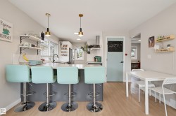 Kitchen with wood-finish flooring, an island with countertop seating, open shelving, and pendant lighting - 