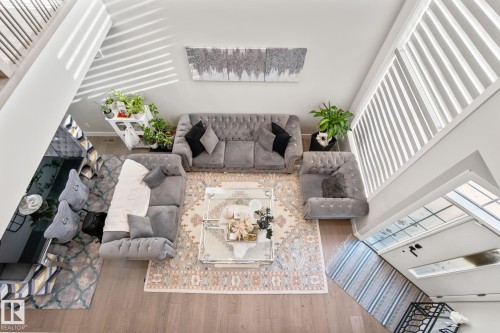 Upper-level perspective of a living area featuring wood-finish flooring, white walls, and a large central area rug - 824 34 Ave Nw, Edmonton, AB 