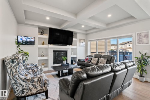 Living area with tray ceiling, recessed lighting, built-in shelving, a fireplace, and wood-finish flooring - 824 34 Ave Nw, Edmonton, AB 