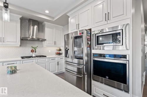 White paneled cabinetry, stainless steel appliances, patterned tile backsplash, gas range, and light-toned countertops - 824 34 Ave Nw, Edmonton, AB 