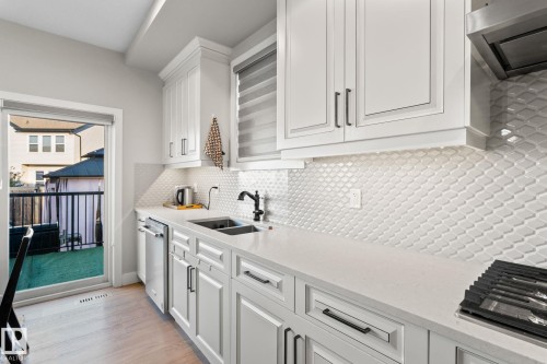 White shaker-style cabinetry, white countertops, textured tile backsplash, stainless steel appliances, and a gas range - 824 34 Ave Nw, Edmonton, AB 