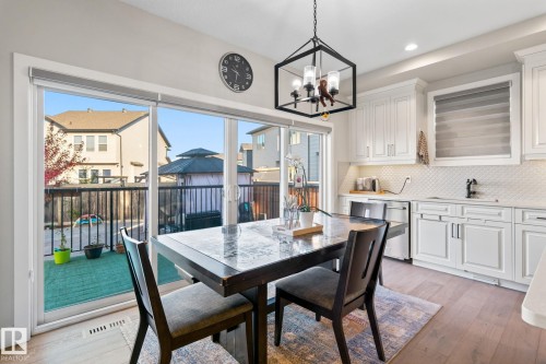 White paneled cabinetry, light wood-finish flooring, white tiled backsplash, sliding glass door, and recessed lighting - 824 34 Ave Nw, Edmonton, AB 
