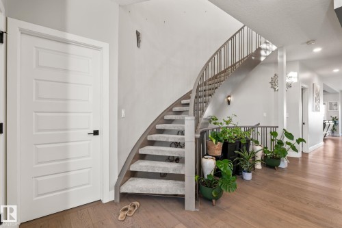 Curved staircase with carpeted treads and metal balusters - 824 34 Ave Nw, Edmonton, AB 