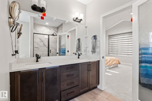 Dual sink vanity with dark wood-finish cabinetry, light-colored countertops, and matte black fixtures - 824 34 Ave Nw, Edmonton, AB 