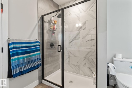 Glass-enclosed shower with black trim, tile surround, and a rain showerhead - 824 34 Ave Nw, Edmonton, AB 