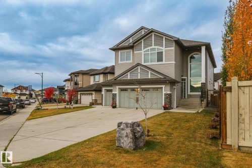 Two-car garage, stone accents, arched window, tall vertical window, and concrete driveway - 824 34 Ave Nw, Edmonton, AB 