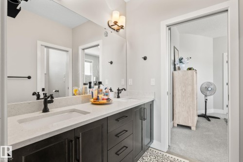 Dual vanity with integrated sinks, light-toned countertop, dark wood-finish cabinetry, and matte black fixtures - 824 34 Ave Nw, Edmonton, AB 