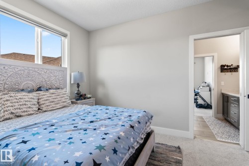 Carpeted room with a large window, white trim, and a doorway to an additional space - 824 34 Ave Nw, Edmonton, AB 
