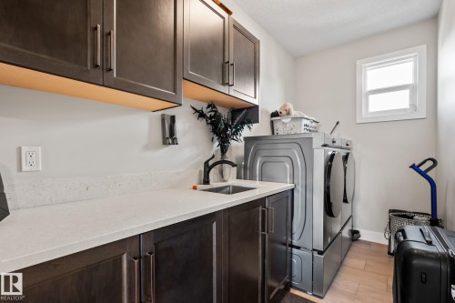 Dark wood-finish cabinetry, light-toned countertop with integrated sink, single window, and light wood-finish flooring - 824 34 Ave Nw, Edmonton, AB 