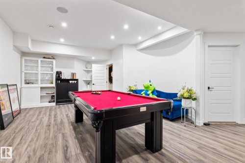 Recessed lighting illuminates the open-concept space featuring wood-finish flooring, a built-in display cabinet, and a built-in beverage bar - 824 34 Ave Nw, Edmonton, AB 