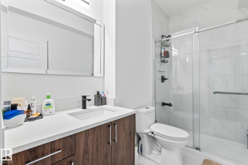 Vanity with a white countertop and dark wood-finish cabinetry, rectangular undermount sink with a matte black faucet, and a large mirrored medicine cabinet - 824 34 Ave Nw, Edmonton, AB 