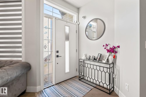 Entryway featuring a decorative console table, white door with glass panels, transom window, and wood-finish flooring - 824 34 Ave Nw, Edmonton, AB 