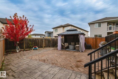 Expansive backyard featuring stamped concrete patio areas, a wooden privacy fence, and a gazebo with privacy curtains - 824 34 Ave Nw, Edmonton, AB 