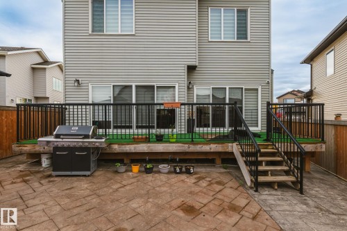 Raised wood deck with black metal railings, leading to a stamped concrete patio - 824 34 Ave Nw, Edmonton, AB 