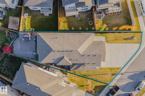 Expansive property featuring a paved driveway, a large shingled roof, a paved patio, and established landscaping - 824 34 Ave Nw, Edmonton, AB 