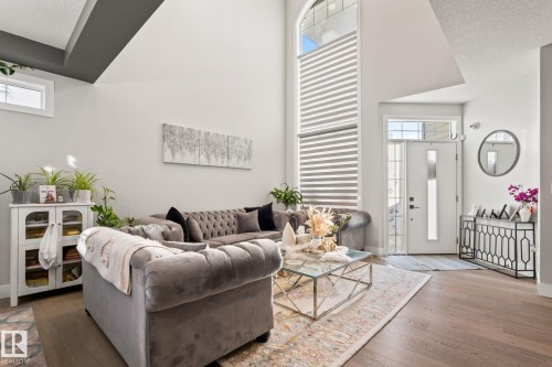 Vaulted ceilings, wood-finish flooring, a contemporary entry door with sidelights, and a prominent arched window with custom blinds - 824 34 Ave Nw, Edmonton, AB 