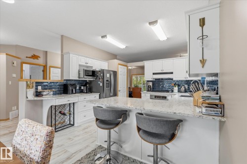 White cabinetry with white countertops, blue subway tile backsplash, and stainless steel appliances - 7 Linkside Pl, Spruce Grove, AB 