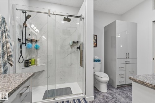Glass-enclosed shower with a rainfall showerhead, integrated shelf, and white subway tile surround - 7 Linkside Pl, Spruce Grove, AB 